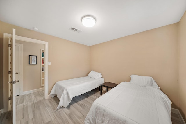 bedroom featuring visible vents, light wood-style flooring, and baseboards