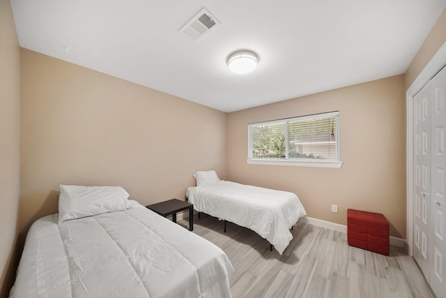 bedroom featuring light wood-style floors, a closet, baseboards, and visible vents