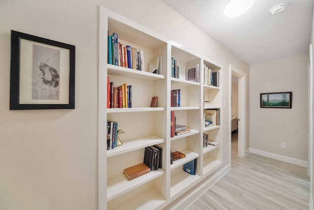 corridor with baseboards and wood finished floors