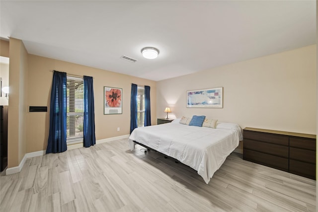 bedroom with light wood-style floors, visible vents, and baseboards