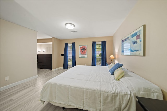 bedroom with visible vents, baseboards, and wood finished floors