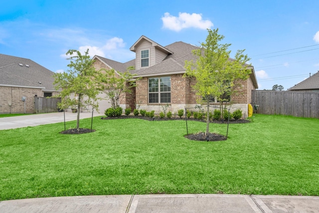 traditional-style house with brick siding, driveway, a front lawn, and fence