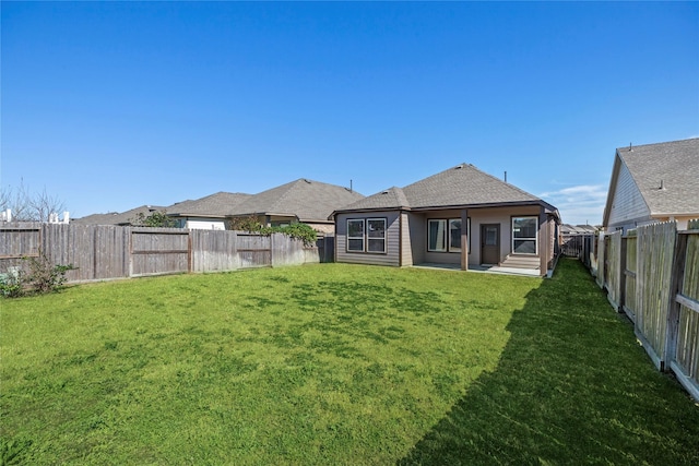 rear view of property with a fenced backyard, roof with shingles, and a yard