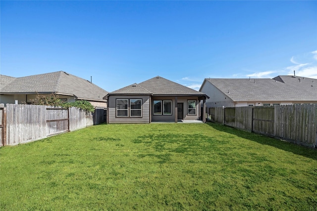 back of house featuring a fenced backyard and a lawn