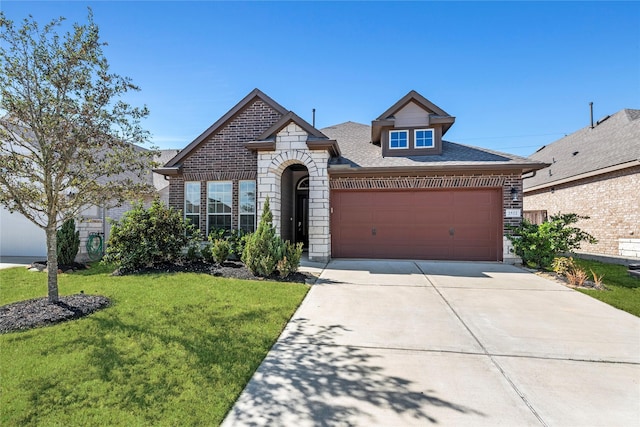 french country home featuring stone siding, brick siding, a front lawn, and concrete driveway