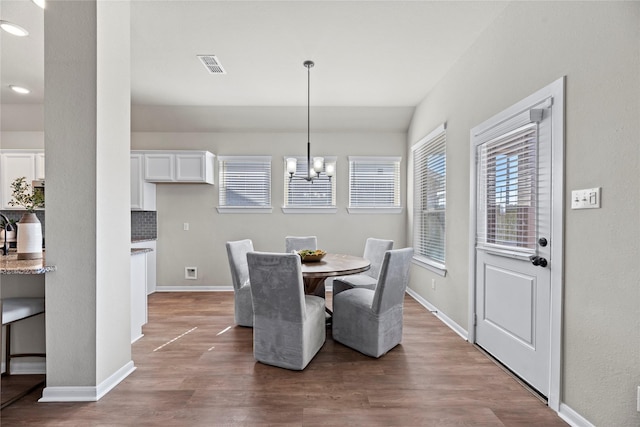 dining room with baseboards, visible vents, a notable chandelier, and wood finished floors