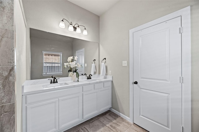 full bathroom featuring baseboards, double vanity, and a sink