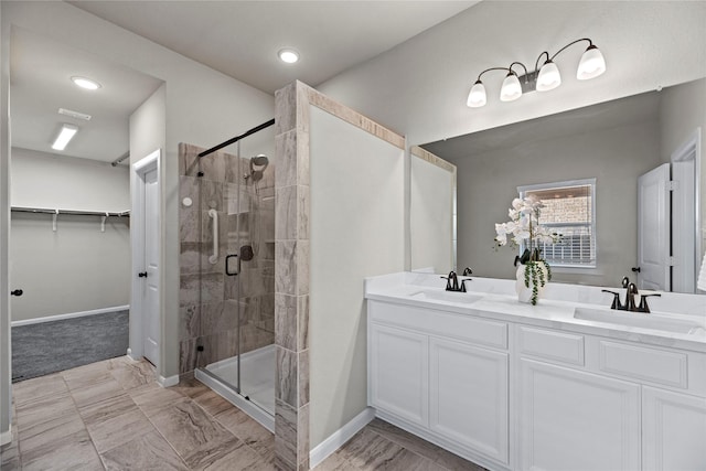 full bath with a shower stall, double vanity, a walk in closet, and a sink