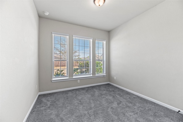 unfurnished room featuring baseboards and dark colored carpet