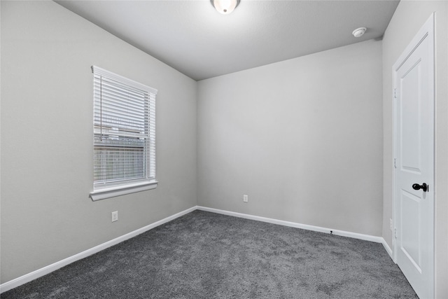 unfurnished room with baseboards and dark carpet