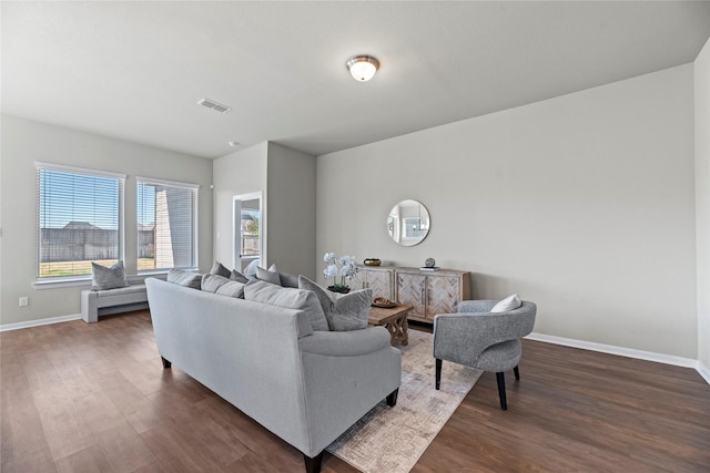 living area with baseboards, visible vents, and dark wood finished floors