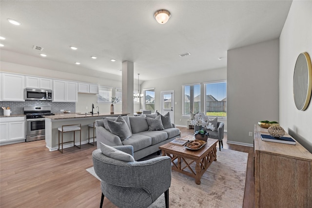 living room featuring visible vents, light wood-style floors, recessed lighting, and an inviting chandelier
