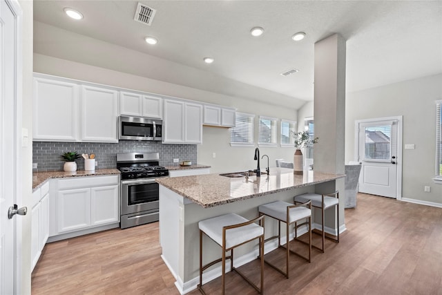 kitchen featuring light stone countertops, light wood-style flooring, a sink, and stainless steel appliances