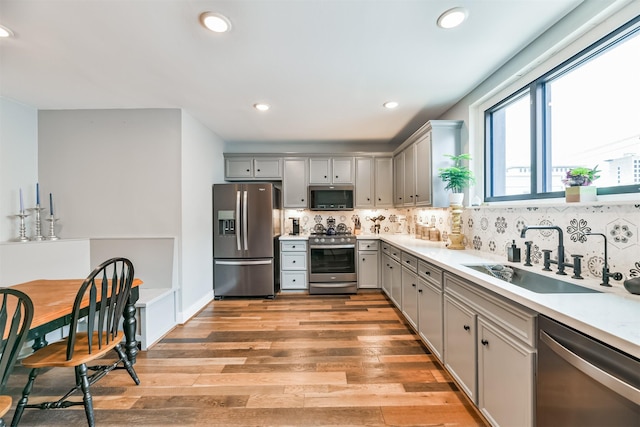 2415 Church St, Galveston, TX 77550 - kitchen with tasteful backsplash, appliances with stainless steel finishes, a sink, light wood-type flooring, and gray cabinetry