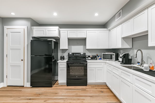 2415 Church St, Galveston, TX 77550 - kitchen with light wood finished floors, white cabinetry, black appliances, and a sink