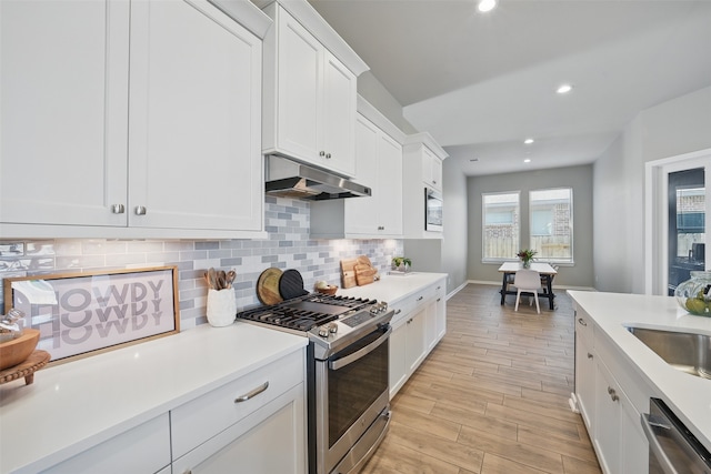 7323 Perching Hawk Trl, Katy, TX 77493 - kitchen featuring under cabinet range hood, light countertops, backsplash, and stainless steel appliances