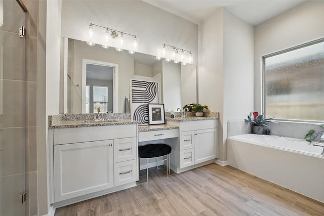 7323 Perching Hawk Trl, Katy, TX 77493 - full bath with two vanities, a bath, a sink, and wood finished floors