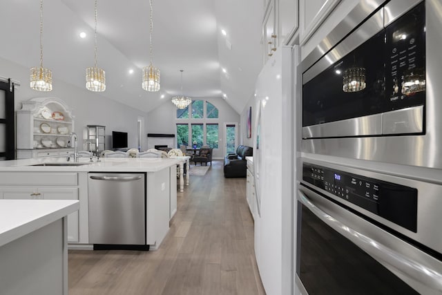 5119 Long Branch Bnd, Fulshear, TX 77441 - kitchen featuring appliances with stainless steel finishes, a sink, vaulted ceiling, light wood-style flooring, and open floor plan