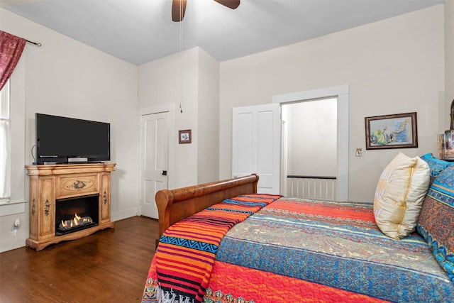 712 Lamar Ave, Crockett, TX 75835 - bedroom featuring a warm lit fireplace, wood finished floors, and a ceiling fan