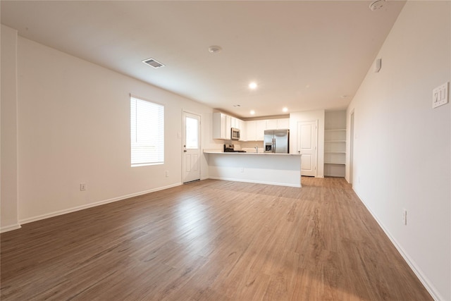 913 Oak Mist Ln, Magnolia, TX 77354 - unfurnished living room with recessed lighting, baseboards, visible vents, and light wood-style floors