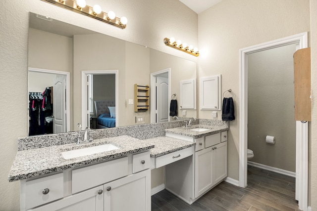 16875 Olympic National Dr, Humble, TX 77346 - ensuite bathroom featuring double vanity, wood finished floors, toilet, and baseboards