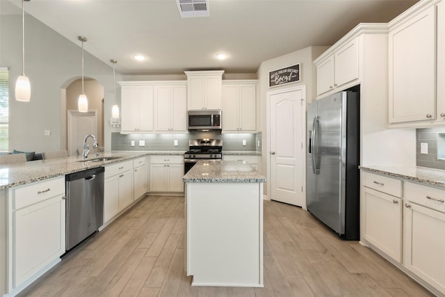 16875 Olympic National Dr, Humble, TX 77346 - kitchen featuring appliances with stainless steel finishes, a sink, arched walkways, a peninsula, and light wood finished floors