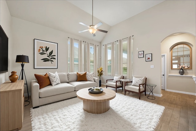 16875 Olympic National Dr, Humble, TX 77346 - living area with arched walkways, vaulted ceiling, a ceiling fan, light wood-style floors, and baseboards