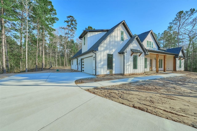 118 Ranger Rd, Huntsville, TX 77340 - view of front of house featuring board and batten siding, concrete driveway, an attached garage, and covered porch
