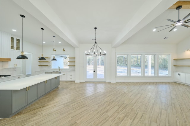 kitchen with light countertops, a sink, open shelves, gray cabinetry, and backsplash