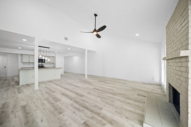 19207 Woodglen Dr, Katy, TX 77449 - unfurnished living room with a brick fireplace, a high ceiling, light wood-style floors, visible vents, and a ceiling fan