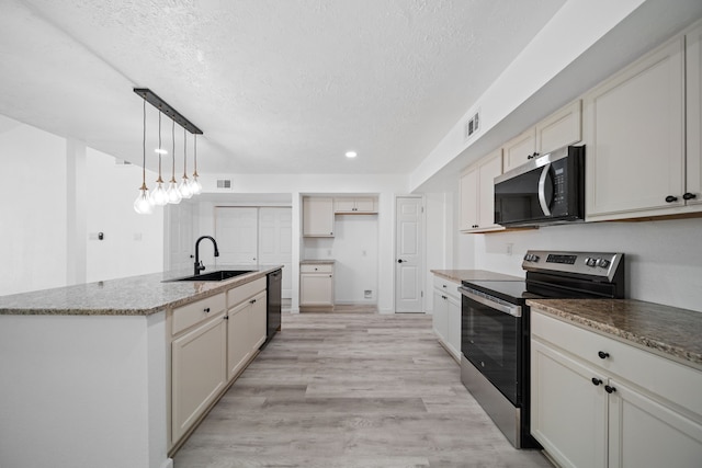 19207 Woodglen Dr, Katy, TX 77449 - kitchen featuring a textured ceiling, light wood-style flooring, a center island with sink, appliances with stainless steel finishes, and a sink