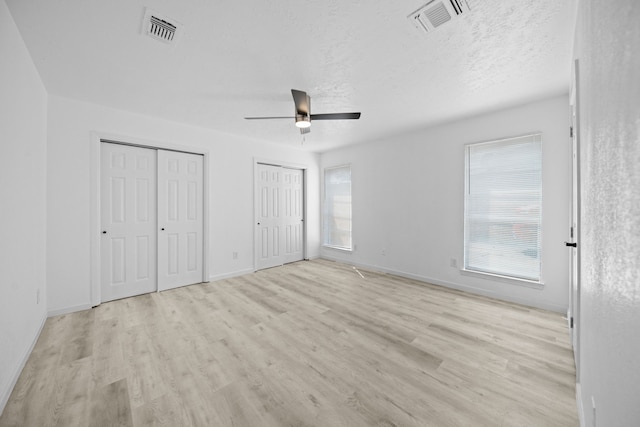 19207 Woodglen Dr, Katy, TX 77449 - unfurnished bedroom with a textured ceiling, visible vents, two closets, and light wood-style floors