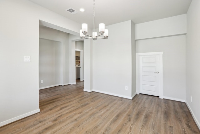 unfurnished room featuring a chandelier, wood finished floors, and baseboards