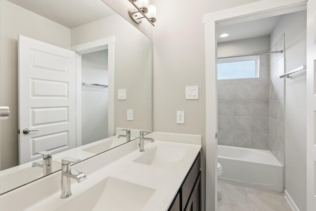 bathroom featuring toilet, double vanity, washtub / shower combination, and tile patterned flooring