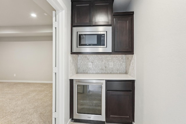 bar with stainless steel microwave, beverage cooler, backsplash, baseboards, and carpet flooring