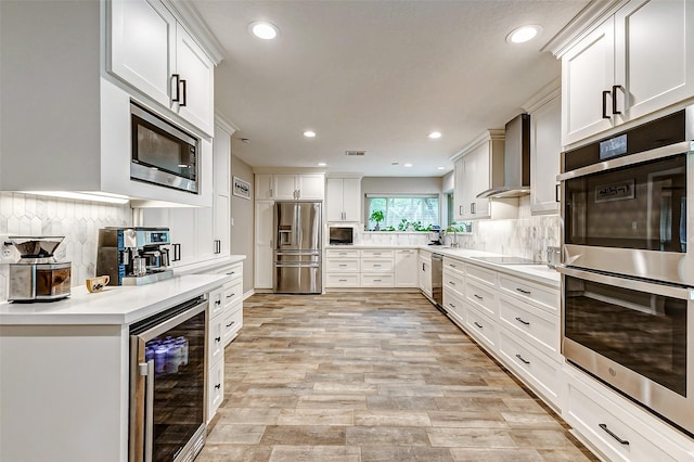 22814 Wren Ln, Tomball, TX 77377 - kitchen featuring wine cooler, appliances with stainless steel finishes, wall chimney range hood, recessed lighting, and tasteful backsplash
