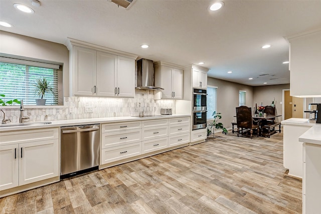 22814 Wren Ln, Tomball, TX 77377 - kitchen featuring appliances with stainless steel finishes, wall chimney exhaust hood, a sink, light countertops, and tasteful backsplash