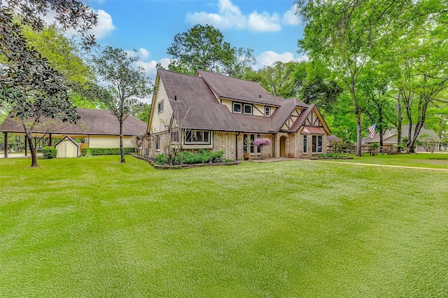 22814 Wren Ln, Tomball, TX 77377 - tudor home with a storage unit, a front lawn, an outbuilding, and brick siding