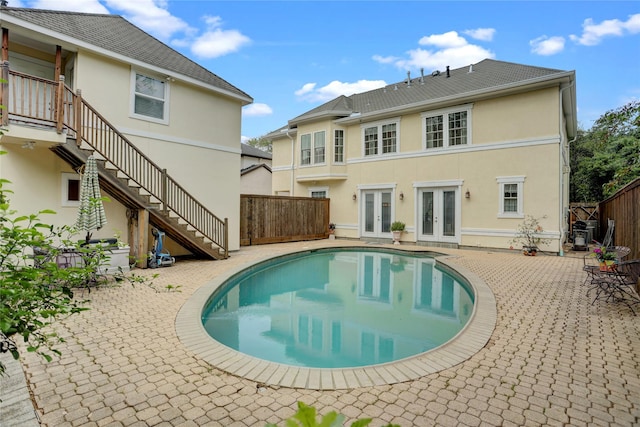 view of swimming pool featuring french doors, stairway, a fenced backyard, and a patio area