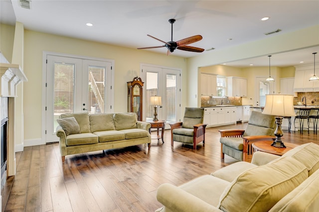 living area with french doors, plenty of natural light, a ceiling fan, hardwood / wood-style flooring, and recessed lighting