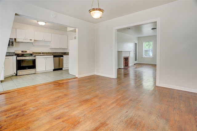 2348 Sheridan St, Houston, TX 77030 - kitchen with stainless steel appliances, under cabinet range hood, a sink, dark countertops, and light wood-style floors