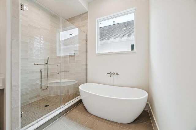 bathroom with tile patterned floors, a soaking tub, a stall shower, and baseboards