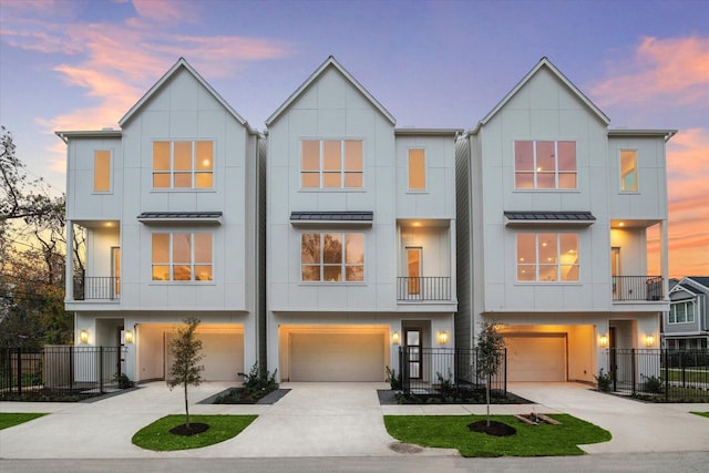 townhome / multi-family property featuring driveway, fence, a standing seam roof, and an attached garage