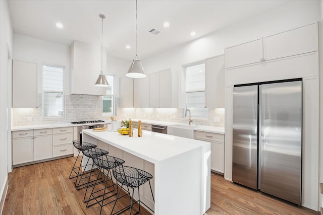 kitchen featuring a kitchen bar, stainless steel appliances, light wood finished floors, and a sink