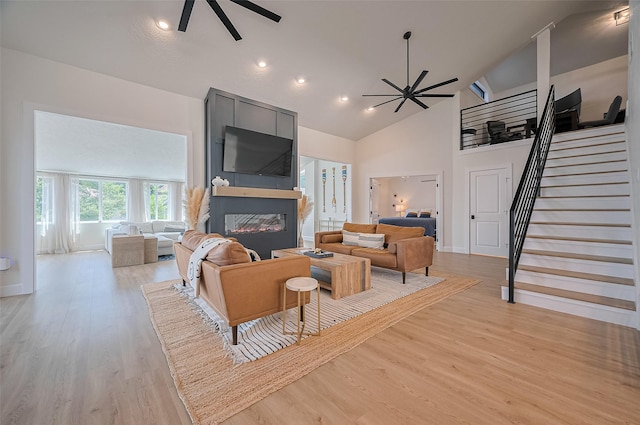 3734 Windswept Dr, Montgomery, TX 77356 - living room featuring ceiling fan, a large fireplace, stairs, light wood-type flooring, and high vaulted ceiling