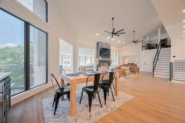 3734 Windswept Dr, Montgomery, TX 77356 - dining area featuring light wood-style floors, stairway, ceiling fan, high vaulted ceiling, and a fireplace