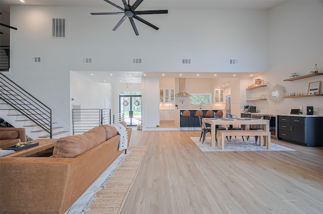 3734 Windswept Dr, Montgomery, TX 77356 - living room featuring a high ceiling, a ceiling fan, stairs, wine cooler, and light wood-style floors