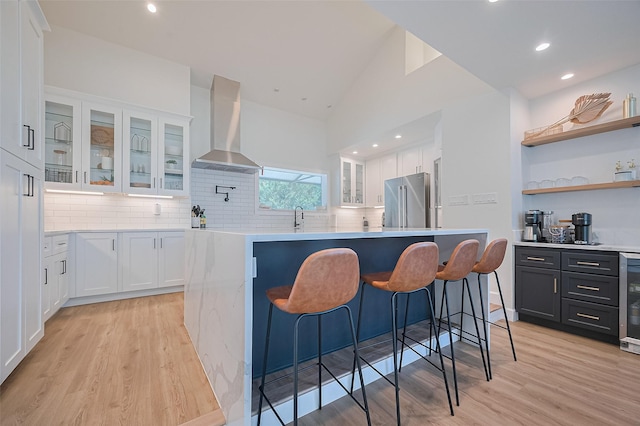 3734 Windswept Dr, Montgomery, TX 77356 - kitchen featuring wall chimney range hood, high quality fridge, white cabinets, light wood-style floors, and recessed lighting