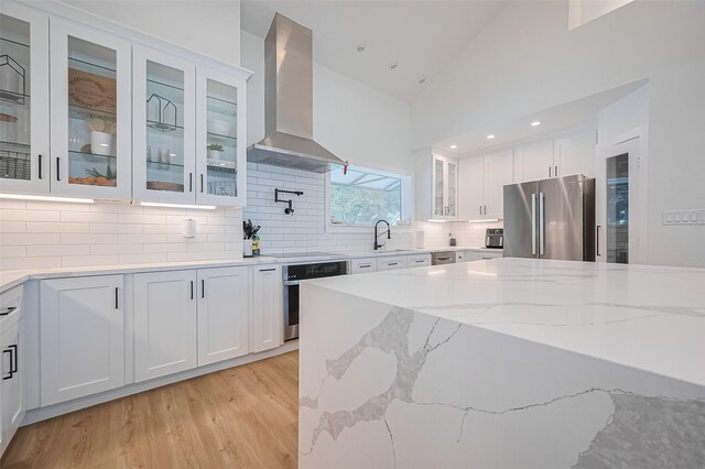 3734 Windswept Dr, Montgomery, TX 77356 - kitchen with appliances with stainless steel finishes, wall chimney range hood, white cabinets, light stone counters, and backsplash