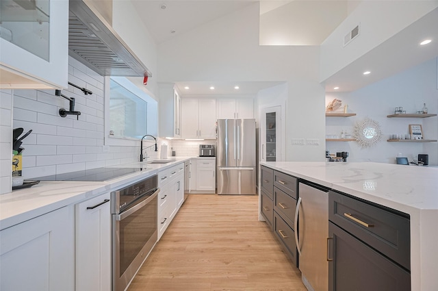 3734 Windswept Dr, Montgomery, TX 77356 - kitchen with appliances with stainless steel finishes, a sink, wall chimney exhaust hood, white cabinetry, and light stone countertops